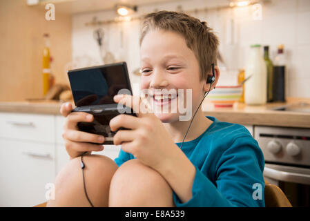 Boy playing video game in kitchen Banque D'Images