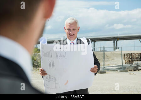 Deux hommes d'affaires avec plan de construction on construction site Banque D'Images