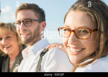 Souriante jeune femme avec deux autres personnes outdoors, portrait Banque D'Images