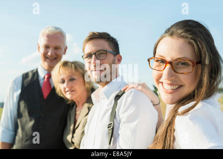 Souriante jeune femme avec trois autres personnes outdoors, portrait Banque D'Images