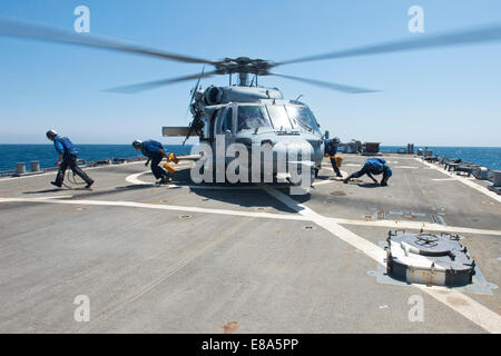 Les marins américains retirer des cales et des chaînes d'un hélicoptère MH-60S Seahawk affectés à l'Escadron d'hélicoptères de combat de la mer (HSC) 26 sur le pont de vol des missiles guidés le destroyer USS Arleigh Burke (DDG 51) dans le golfe Persique le 6 septembre 2014. L'Arleigh Burke Banque D'Images