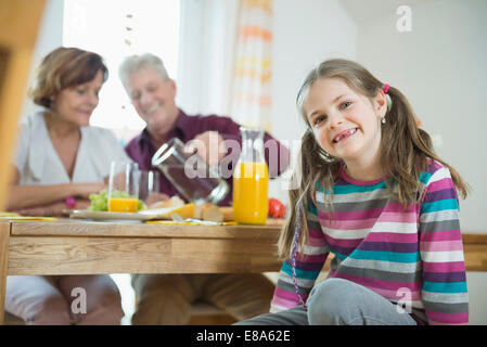 Les grands-parents et petite-fille, souriant having meal Banque D'Images