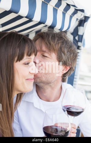 Couple having vine en osier couvert chaise de plage, smiling Banque D'Images
