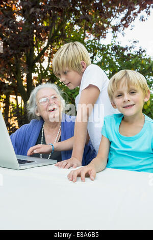 Grand-mère et ses deux petits-fils avec portable Banque D'Images