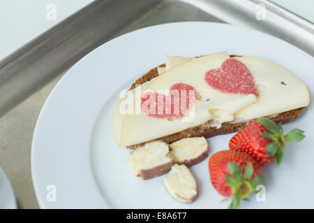 Du pain avec du fromage, de la fraise et de salami en forme de coeur sur la plaque, Close up Banque D'Images