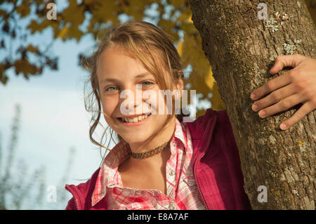 Girl holding tronc d'arbre, smiling, portrait Banque D'Images