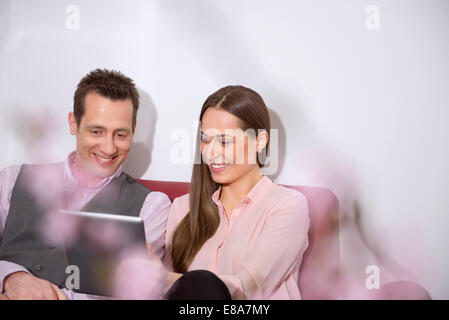 Young couple looking at tablet computer smiling Banque D'Images