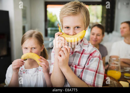 Frère et sœur s'amusant avec deux bananes Banque D'Images