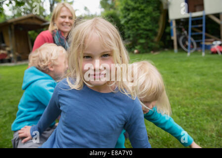 Mère jouant avec trois jeunes enfants dans jardin Banque D'Images