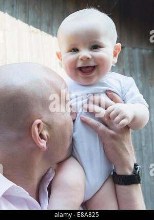 Père holding baby son fier rire heureux Banque D'Images