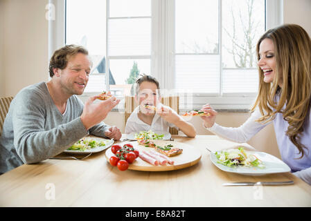 Family eating pizza et salade à la maison Banque D'Images