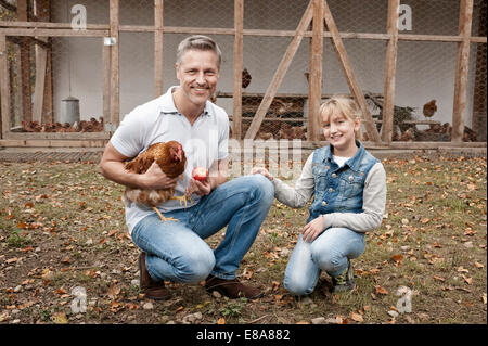 Père et fille avec du poulet à la ferme biologique Banque D'Images