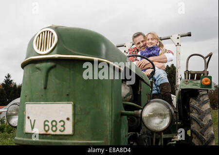 Farmer hugging daughter sur le tracteur Banque D'Images