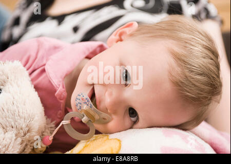 Fatigué bébé fille 18 mois au lit avec dummy Banque D'Images