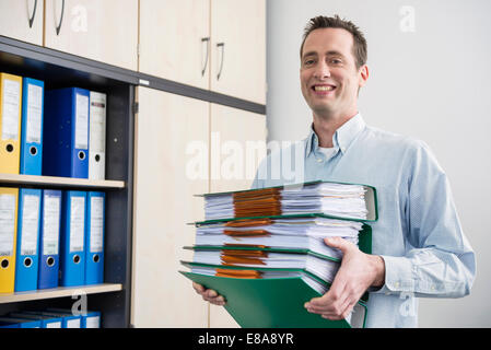 Portrait man carrying pile de dossiers de dépôt Banque D'Images