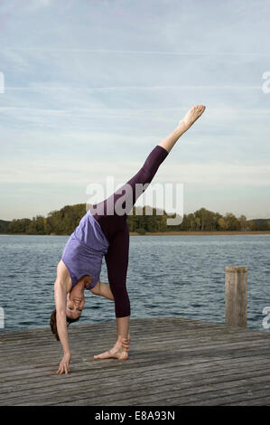 Woman practicing yoga on Jetty, Woerthsee, Bavière, Allemagne Banque D'Images