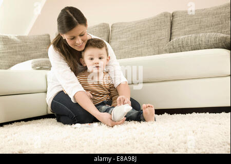 Mother putting chaussettes sur fils, smiling Banque D'Images