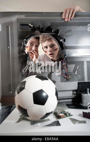 Deux adolescents regardant choqué ballon de soccer démolir plat Banque D'Images