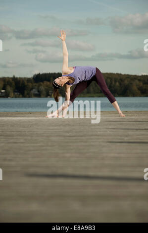 Woman practicing yoga on Jetty, Woerthsee, Bavière, Allemagne Banque D'Images