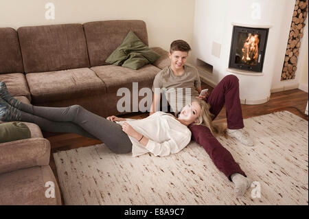 Teenage couple sur la moquette en face de feu Banque D'Images