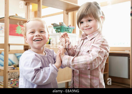 Deux smiling little girls holding hands in Kindergarten Banque D'Images