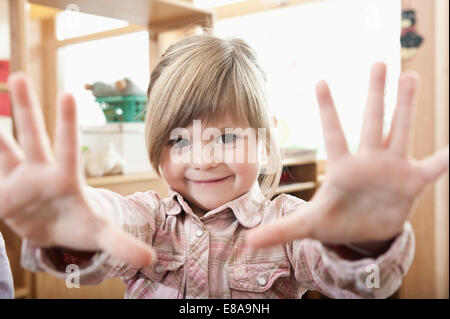 Portrait of smiling little girl montrant ses mains Banque D'Images