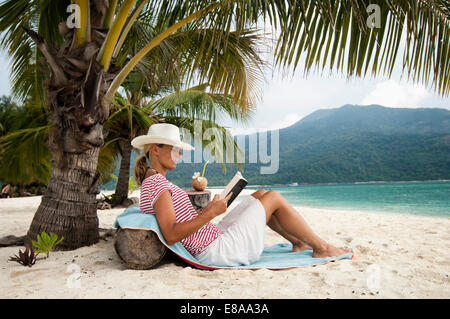 Femme lisant un livre sur la plage, Koh Lipe, Thaïlande Banque D'Images