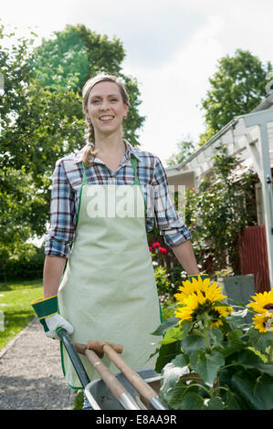 Portrait woman pushing wheelbarrow jardin Banque D'Images