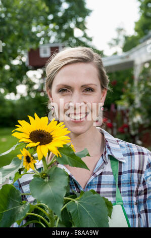 Portrait of smiling woman holding sunflower Banque D'Images