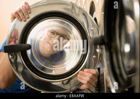 Jeune homme à la fenêtre grâce à des lave-linge, smiling Banque D'Images