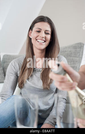 Portrait de jeune femme en regardant son amie, tout en ouvrant une bouteille de champagne Banque D'Images