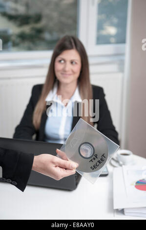 Hand holding CD, jeune femme d'affaires assis dans l'arrière-plan Banque D'Images