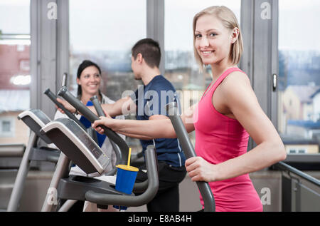 Jeune femme sur elliptical trainer in gym Banque D'Images