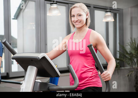 Jeune femme sur elliptical trainer in gym Banque D'Images