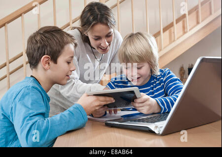 Deux garçons et filles enfants assistant avec ordinateur portable et tablette ordinateur Banque D'Images