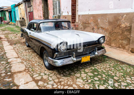 Scène de rue avec voiture d'époque et bâtiments usés à Trinidad, Cuba. Banque D'Images