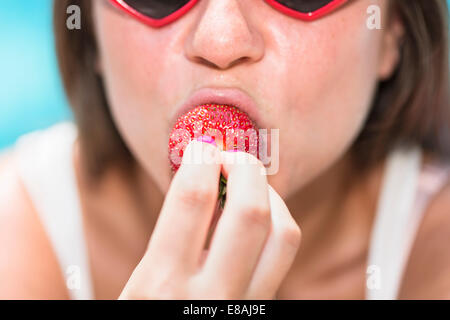 Cropped portrait of young woman biting strawberry Banque D'Images