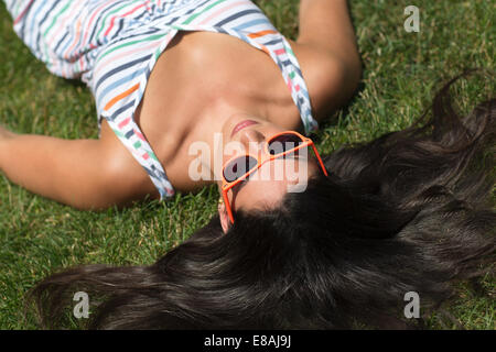 Jeune femme portant sur la pelouse de bronzage sundress Banque D'Images