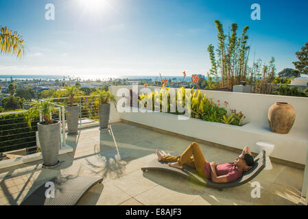 Jeune homme allongé sur une chaise longue dans le jardin sur le toit, La Jolla, Californie, USA Banque D'Images