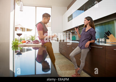 Couple chatting et boire du vin alors que la cuisson dans la cuisine Banque D'Images