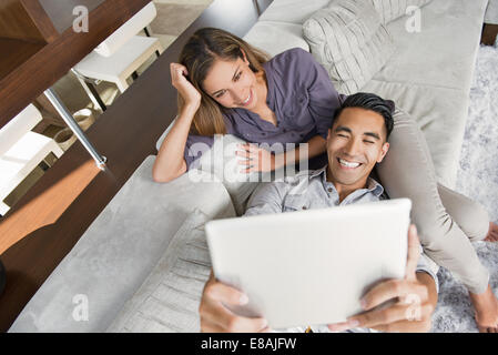 Couple sur salon canapé en tenant avec selfies digital tablet Banque D'Images