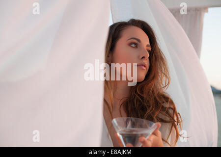 Jeune femme avec verre à cocktail au beach gazebo, Castiadas, Sardaigne, Italie Banque D'Images