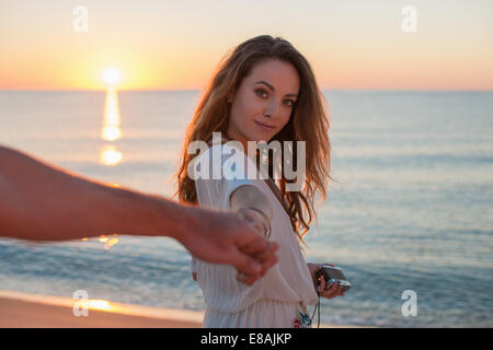 Jeune femme tenant la main de petits amis au coucher du soleil sur la plage, Castiadas, Sardaigne, Italie Banque D'Images