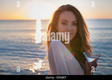 Portrait of young woman on beach avec cocktail au coucher du soleil, Castiadas, Sardaigne, Italie Banque D'Images