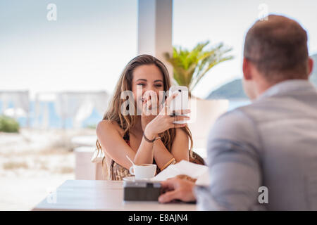 Young woman taking photograph of boyfriend sur smartphone à plage, Castiadas, Sardaigne, Italie Banque D'Images