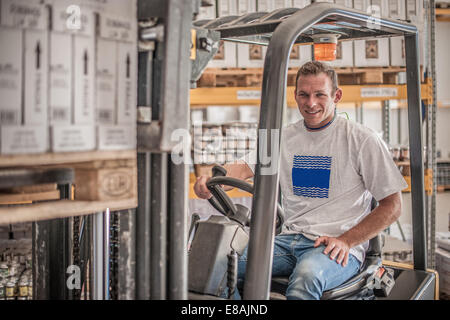 Portrait de jeune conducteur de chariot élévateur dans l'usine-entrepôt Banque D'Images