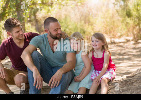 Homme couple sitting on riverbank avec deux filles Banque D'Images