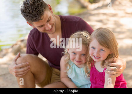 Portrait de père et deux filles on riverbank Banque D'Images