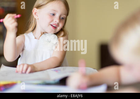 Deux soeurs dans les livres de coloriage avec des crayons de couleur dans la salle de séjour Banque D'Images