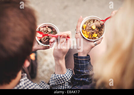 Couple eating de pots de yaourt glacé traiter Banque D'Images